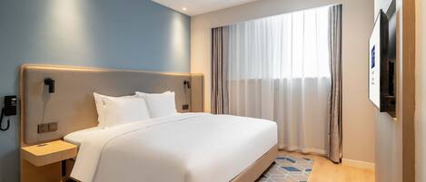 Una habitación de hotel moderna con una cama grande, una mesita de noche, un teléfono en la pared y una ventana con cortinas.