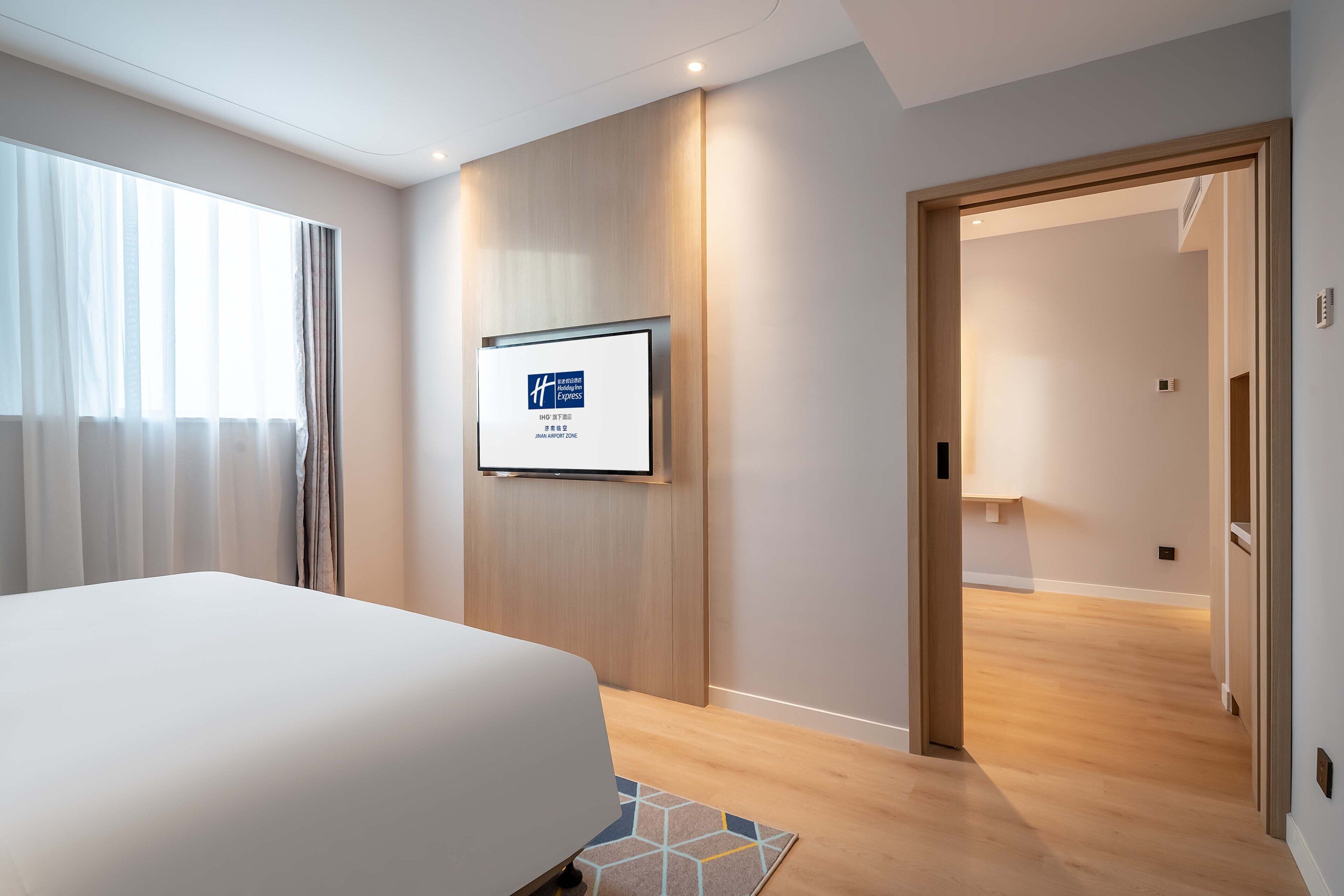 Een hotelkamer met een bed, een tv aan de muur en een houten vloer.