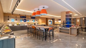 Una cocina moderna con una isla central, taburetes de bar y una zona de buffet con diversas opciones de comida.