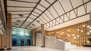 Un lobby amplio con techo alto, una escalera y una pared con paneles iluminados.