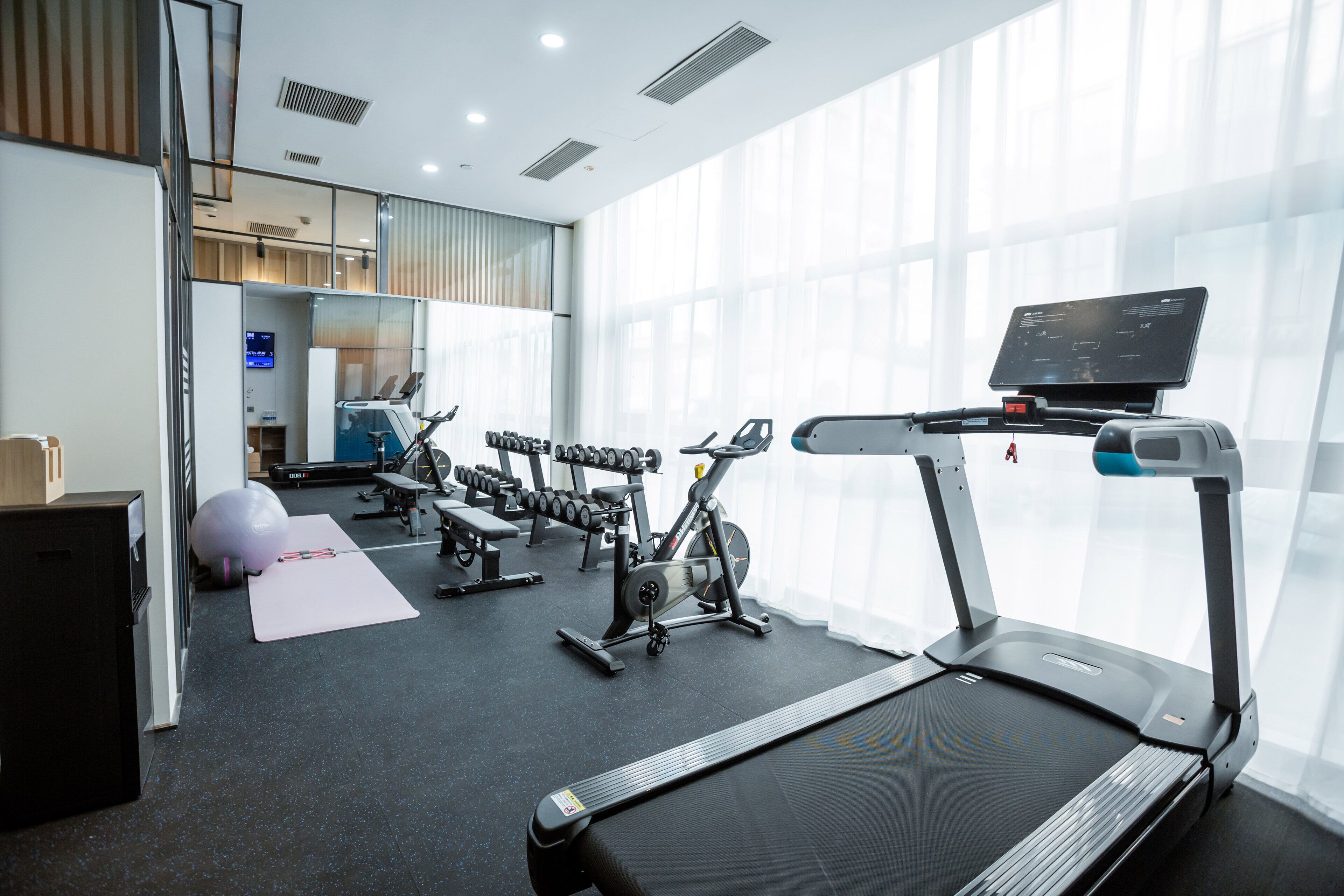 A modern gym with treadmills, dumbbells, and exercise balls.
