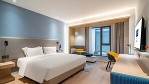 Una habitación de hotel moderna con una cama grande, un escritorio, una silla y un televisor.