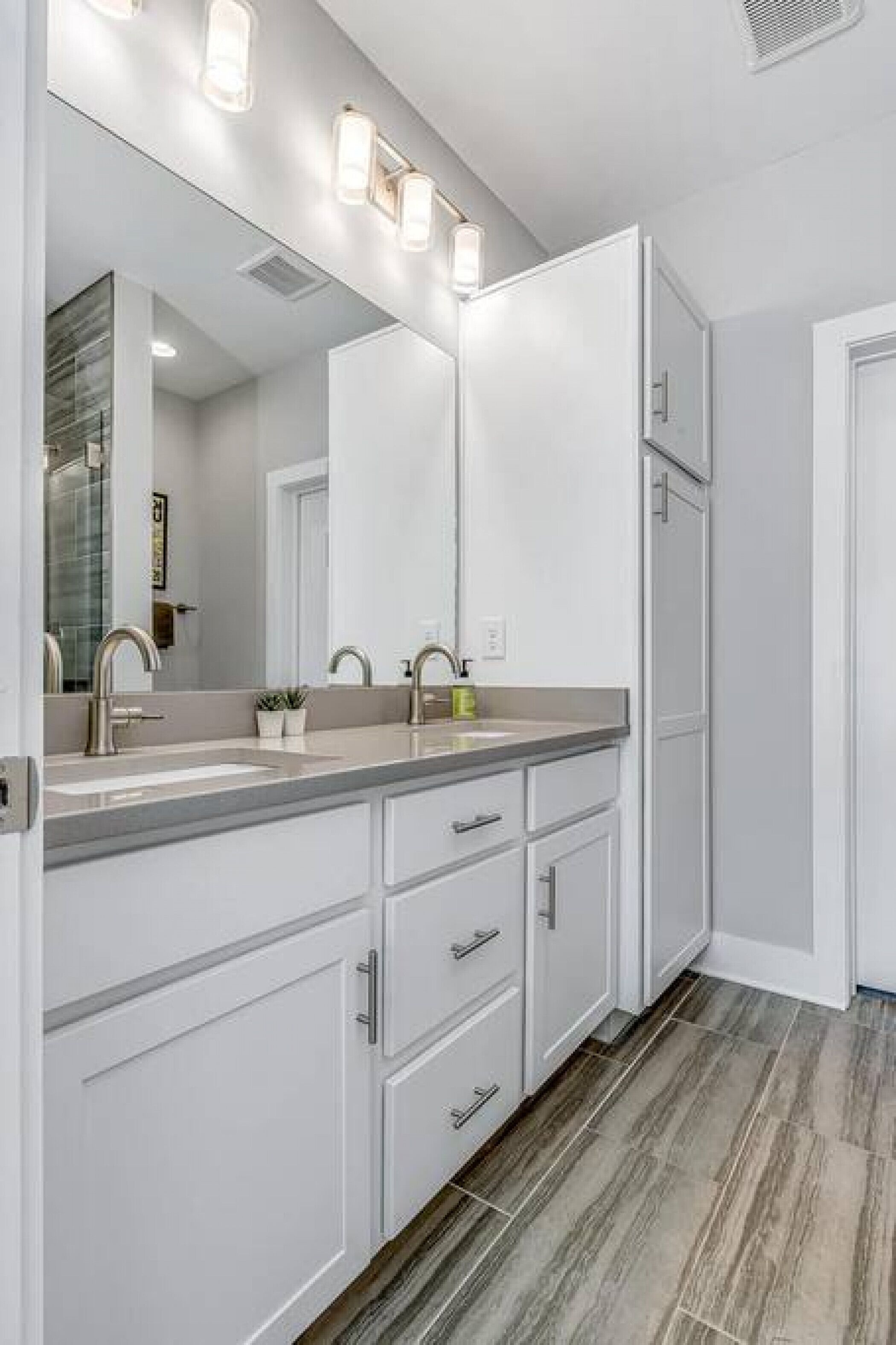 Une salle de bain moderne avec un meuble-lavabo à deux vasques, un grand miroir et des appliques murales éclairées.