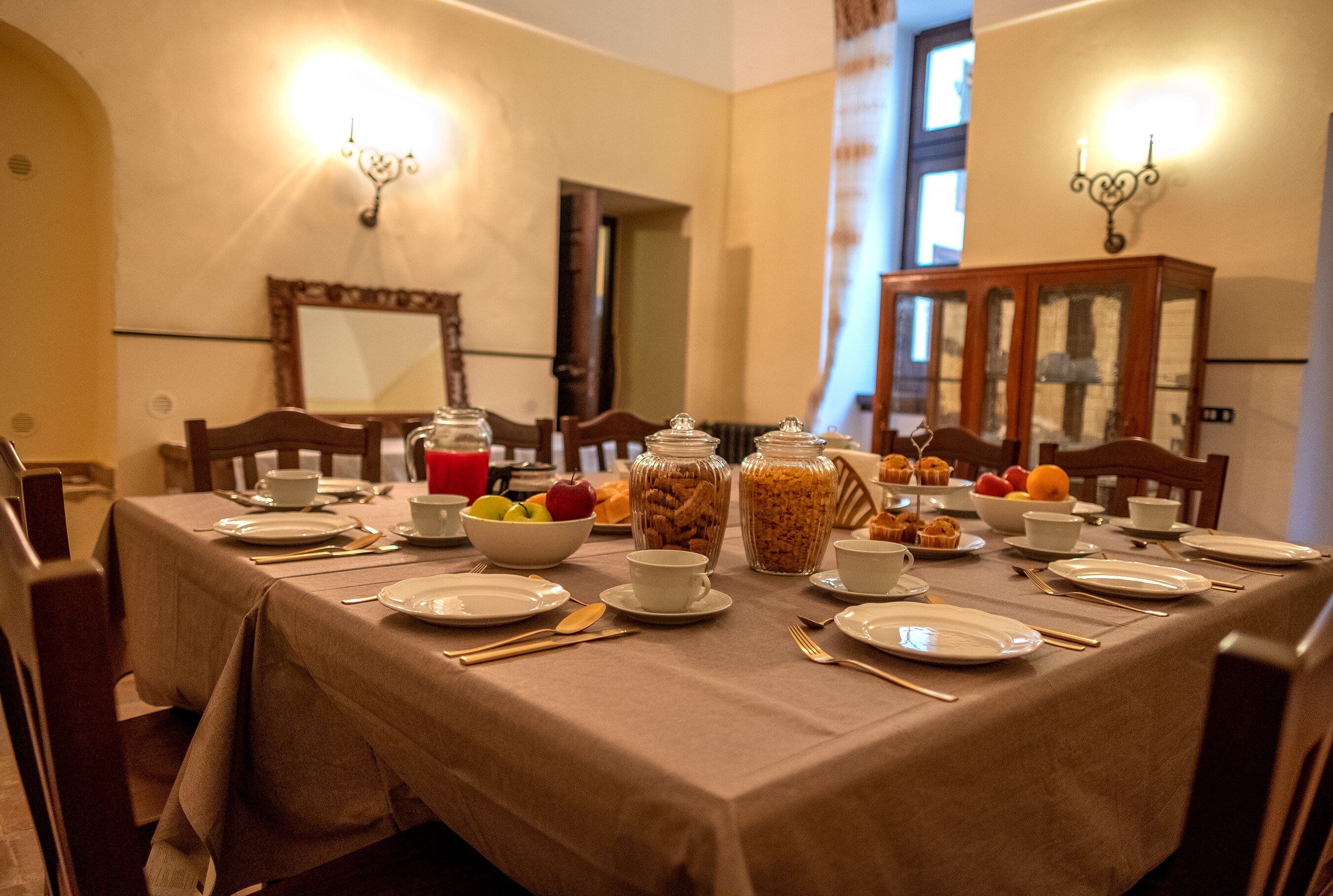 A dining table set for breakfast with various food items and utensils.