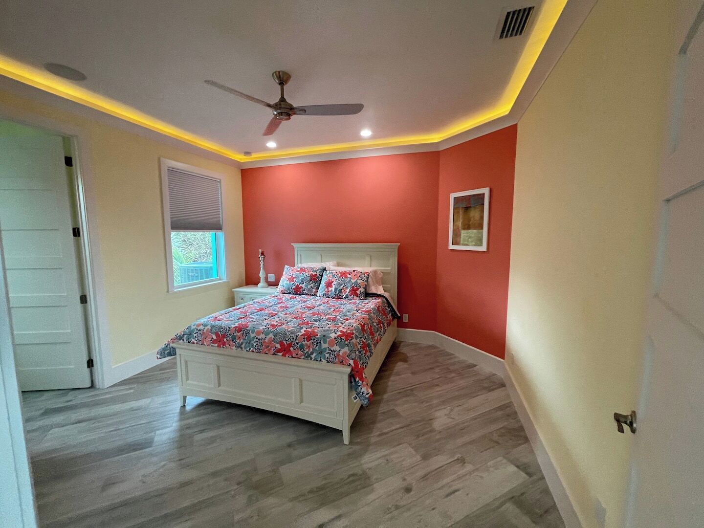 Una camera da letto con un letto, un ventilatore a soffitto e una finestra con persiane.
