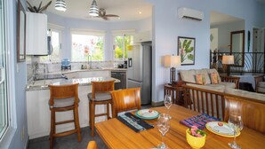 Une cuisine moderne avec un îlot central, un coin repas avec des meubles en bois et un salon comprenant un canapé et une table basse.