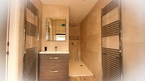 Un baño moderno con un espejo grande, un lavabo y una zona de ducha.