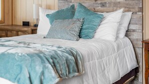 A bed with a wooden headboard, white and teal pillows, and a gray pillow with the word "kissed" on it. - South Shore Lake House Haven (Edinburg)