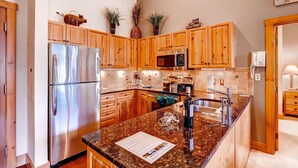 A modern kitchen with wooden cabinets, stainless steel appliances, granite countertops, and a built-in oven. - River Run by Wyndham Vacation Rentals (Keystone)