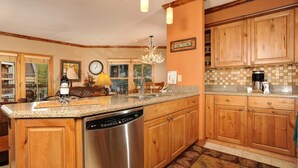 A spacious kitchen with wooden cabinets, a granite countertop, and a dishwasher. - River Run by Wyndham Vacation Rentals (Keystone)