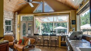 A cozy patio area with wicker furniture, a grill, and a view of the outdoors.