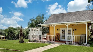 A yellow house with a porch, white railing, and a satellite dish.