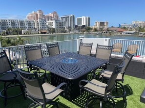 A patio with a table and chairs overlooking a marina and city skyline.