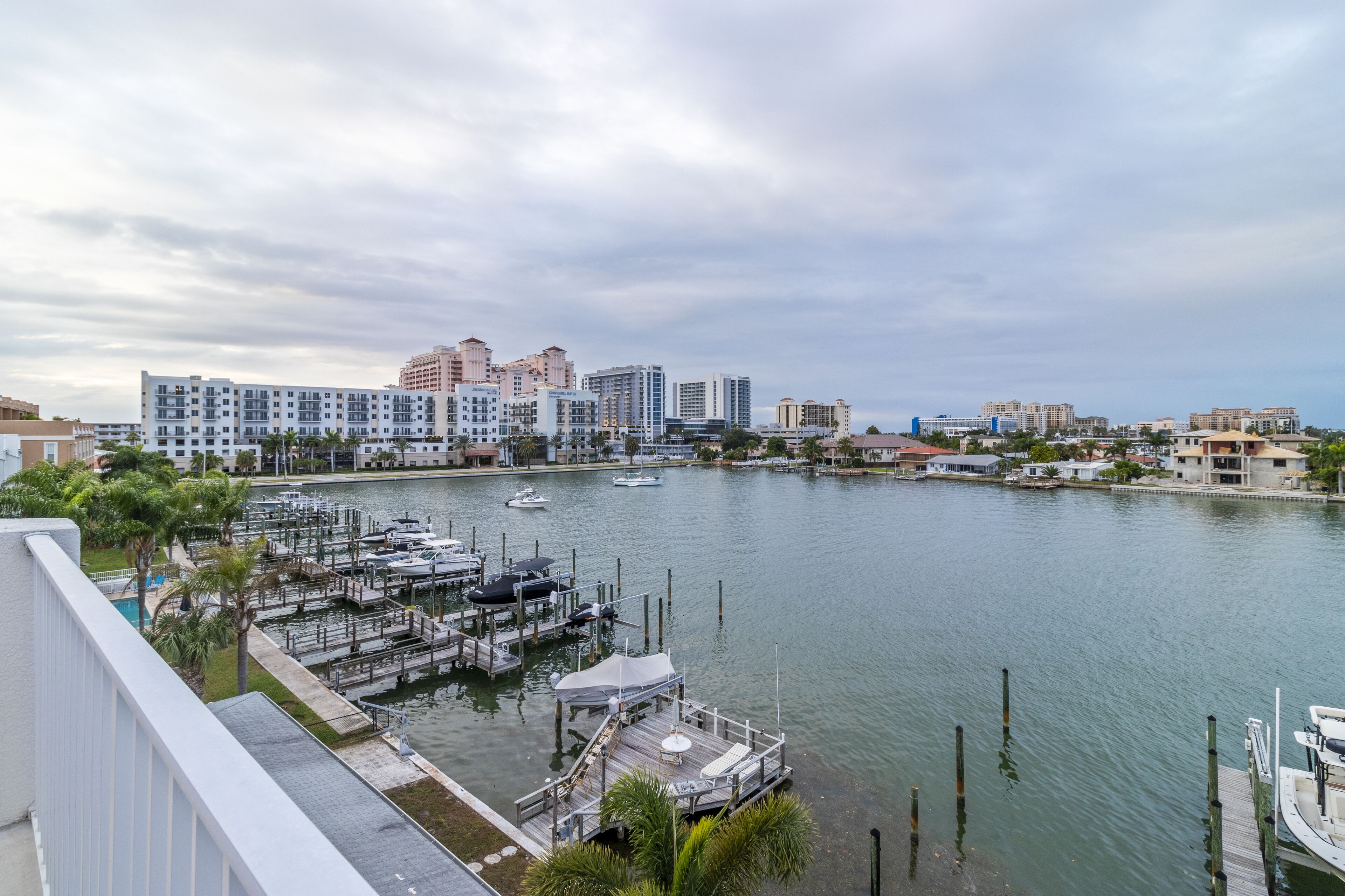 A marina with boats docked, a waterfront view, and buildings in the background.