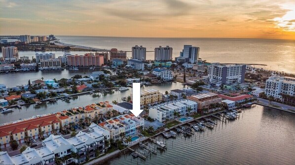 A coastal cityscape with a marina, buildings, and a sunset.