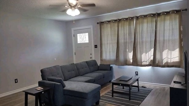 A living room with a sectional sofa, a coffee table, a TV, and a ceiling fan.