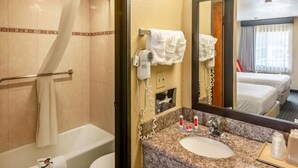 Une salle de bain d’hôtel équipée d’une douche, d’un lavabo, d’un miroir et d’un porte-serviettes.