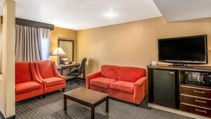 Une chambre d’hôtel équipée d’un canapé, d’un fauteuil, d’un bureau, d’une télévision et d’un mini-réfrigérateur.