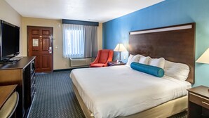 Una habitación de hotel con una cama grande, televisión, escritorio y una silla.