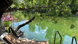 A serene outdoor seating area with a lounge chair and a hammock by a calm pond, surrounded by lush greenery. - House on the river, private pool, garden and barbecue . 2hours to Dubrovnik! (Malo Polje)