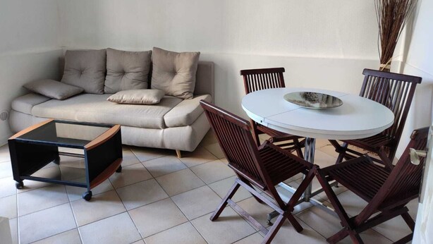 Ein modernes Wohnzimmer mit einer Couch, einem Esstisch mit Stühlen und einem kleinen Rollwagen.