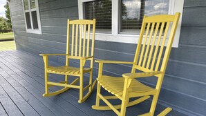 Two yellow rocking chairs on a wooden deck in front of a house with gray siding and white trim. - Sleeps 5 (unit 4b), pool, next to Big M Marina, 15 min to Roaring River (Cassville)
