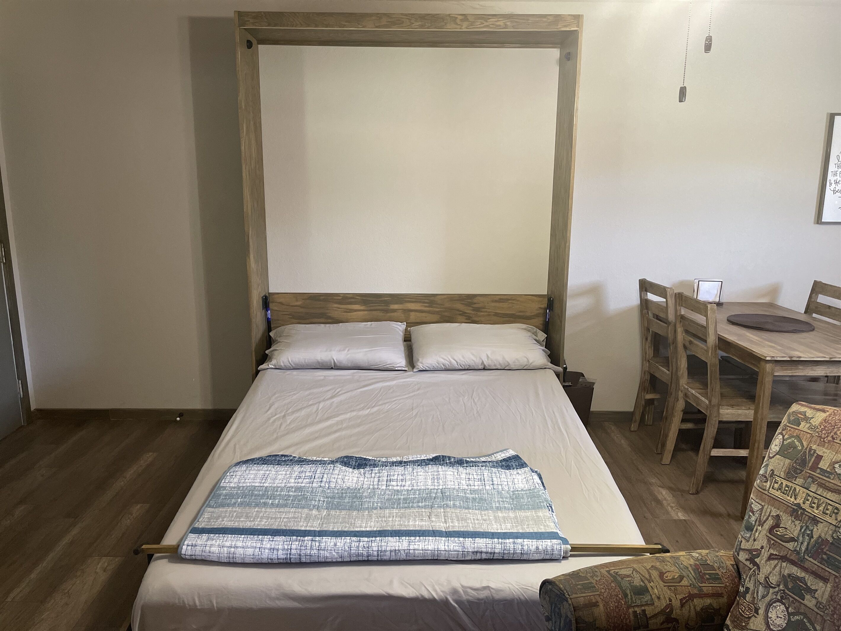 A single bed with a wooden headboard, a bedside table, and a chair.