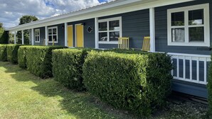 A single-story house with a covered porch, two doors, and a small garden area with hedges. - Sleeps 5 (unit 4b), pool, next to Big M Marina, 15 min to Roaring River (Cassville)