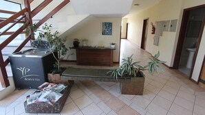 A reception area with a reception desk, a staircase, and several potted plants. - Pousada Porto do Arvoredo (Florianópolis)