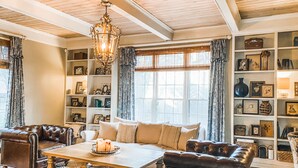 A cozy living room with a wooden coffee table, leather sofas, and a chandelier. - Spacious Historic Midtown Memphis Chateau Minutes from Everything  (Memphis)