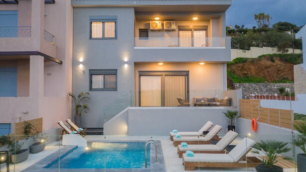 A modern building with a pool, lounge chairs, and a balcony with seating. - Emmeleia mare new building maisonette with pool, seaview, 3 min from the beach  (Αγία Πελαγία)