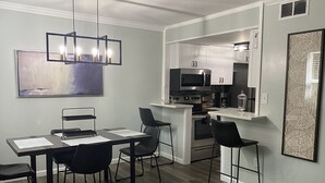A modern kitchen with stainless steel appliances, a dining area with a table and chairs, and a contemporary light fixture. - Newly Renovated Cozy/Modern Pet-Friendly Villa for the entire family to enjoy. (Hilton Head Island)