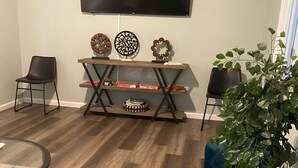 A living room with a flat-screen TV mounted on the wall, a wooden coffee table, a blue rug, and a potted plant. - Newly Renovated Cozy/Modern Pet-Friendly Villa for the entire family to enjoy. (Hilton Head Island)