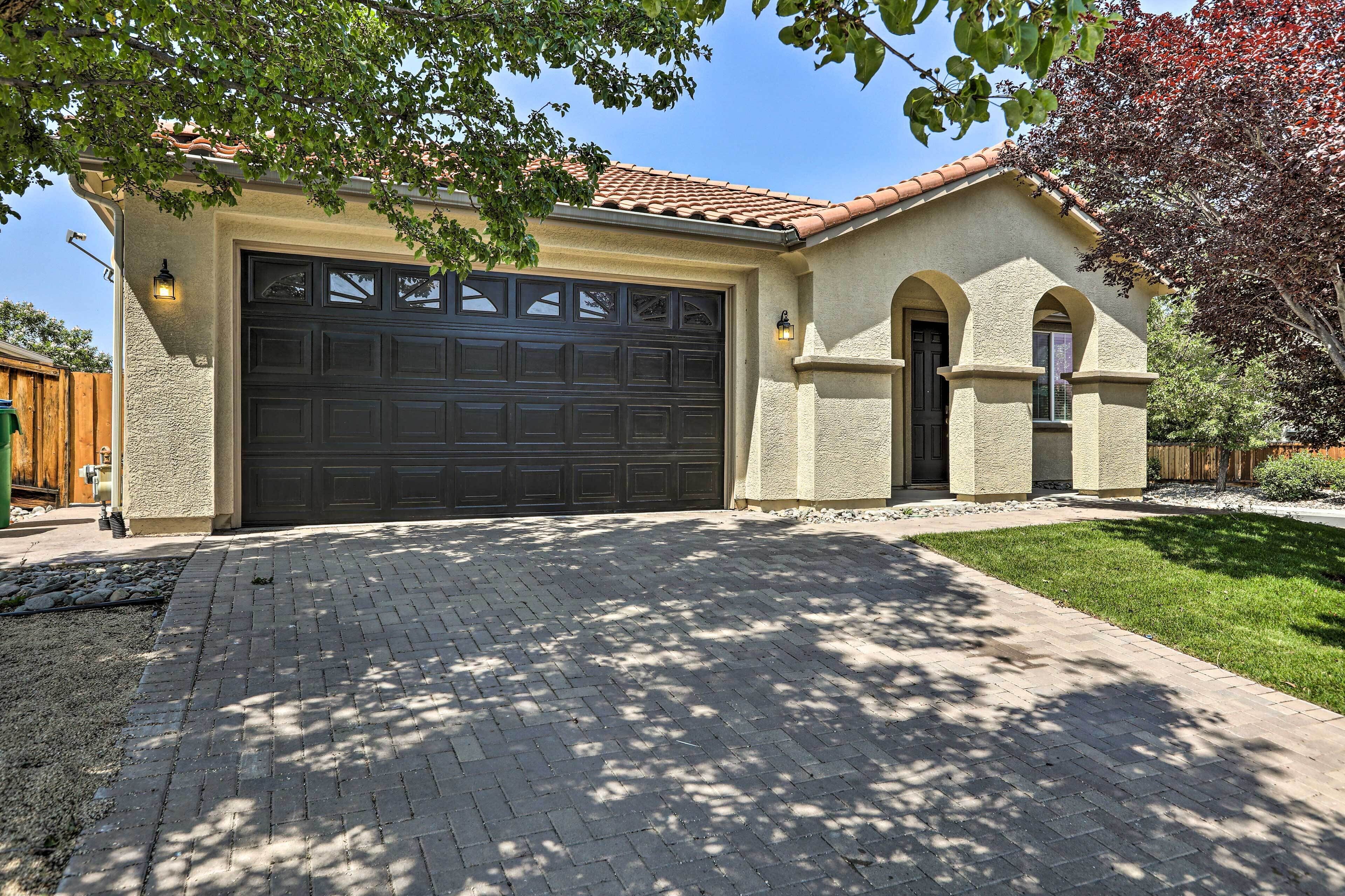 Une maison avec un grand garage, une allée pavée en briques et une pelouse bien entretenue.