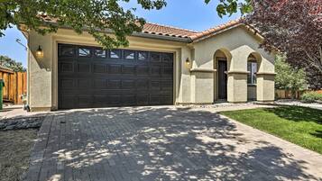 Une maison avec un grand garage, une allée pavée en briques et une pelouse bien entretenue.