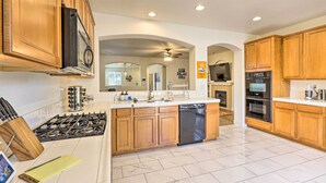 A modern kitchen with wooden cabinets, a central island with a dishwasher, a stove, and an oven. - 12 Mi to Riverwalk District: Quiet Reno Retreat (Reno)