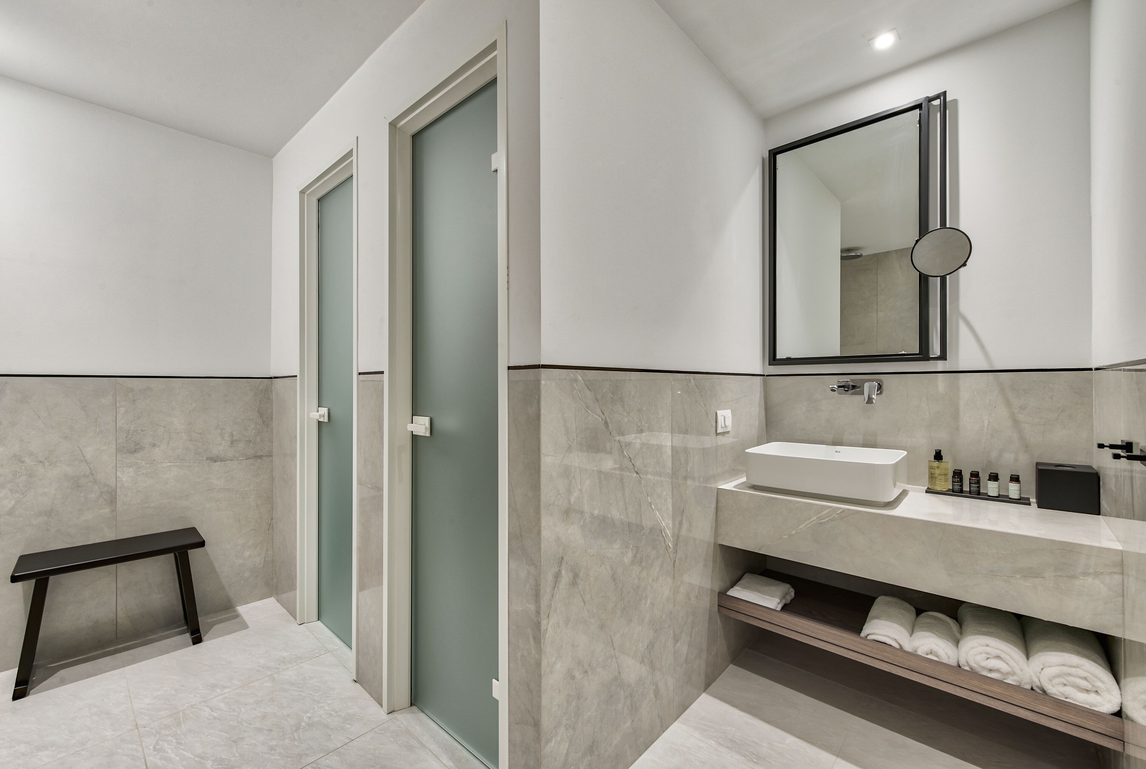 Een moderne badkamer met een bankje, een wastafel en een spiegel.