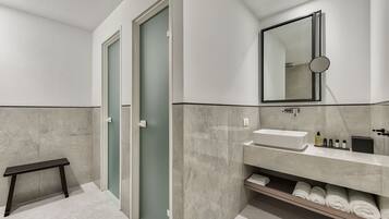 Een moderne badkamer met een bankje, een wastafel en een spiegel.