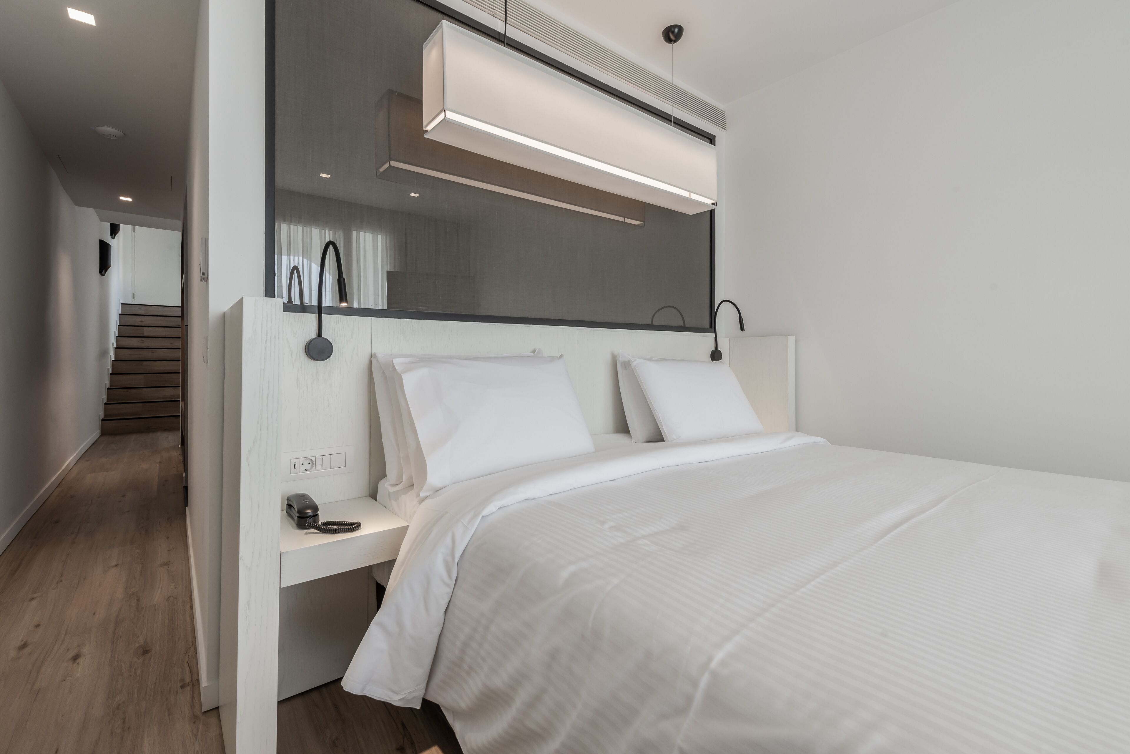 Camera da letto moderna con un letto grande, un comodino con una lampada e un condizionatore integrato sopra il letto.