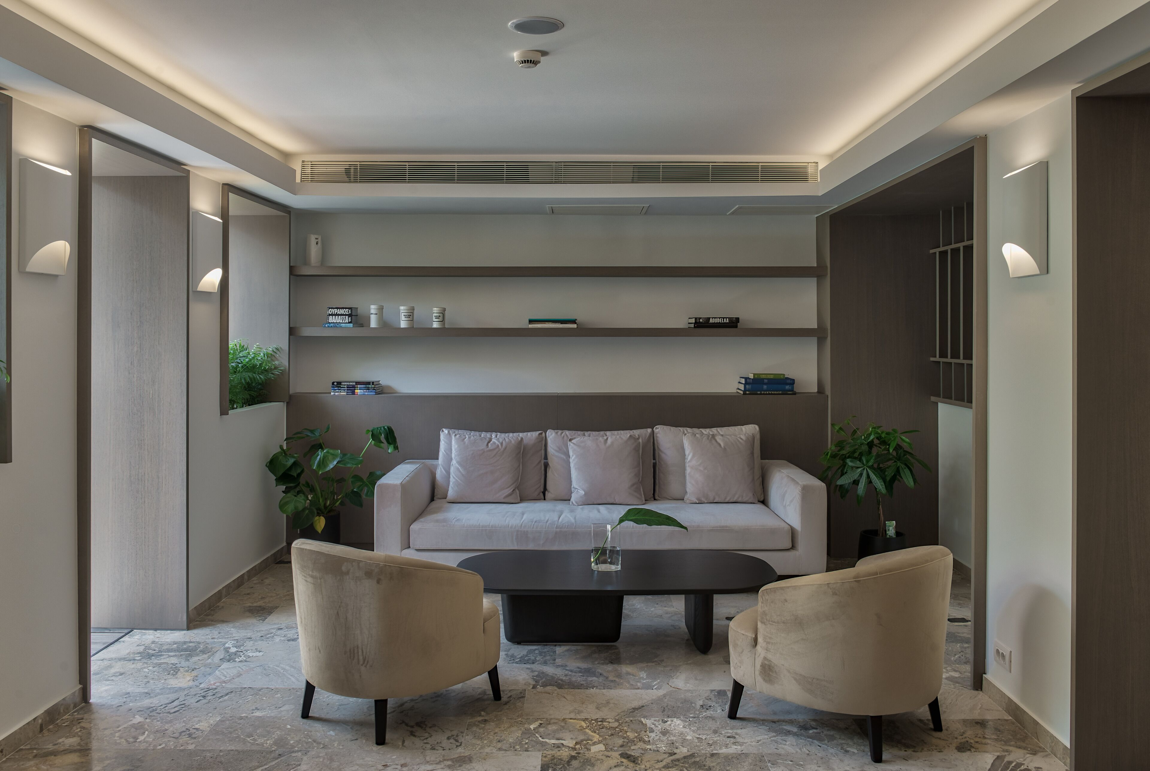 Una sala de estar moderna con un sofá, dos sillones, una mesa de centro y una planta en maceta.