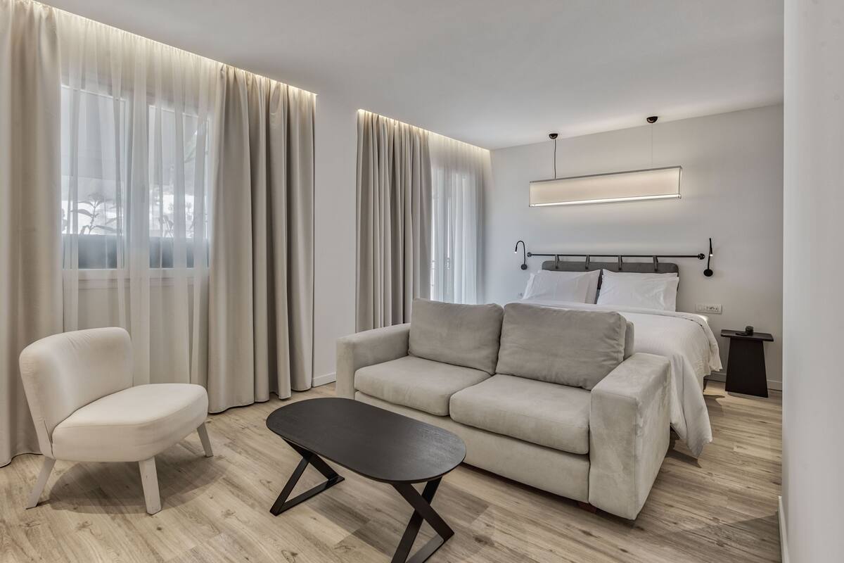 Une chambre d’hôtel moderne avec un canapé, un fauteuil et une petite table.