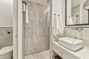 A modern bathroom with a glass shower enclosure, a white sink, and a large mirror.