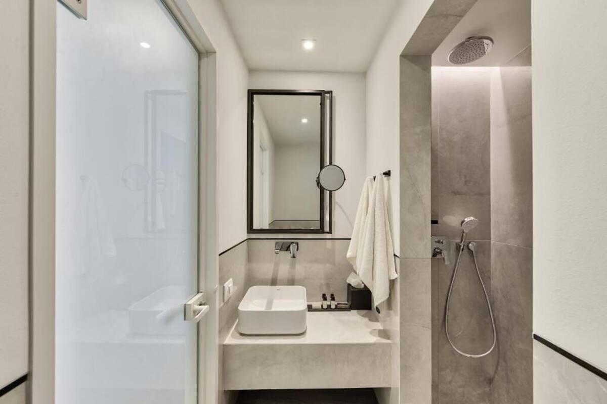 Une salle de bain moderne avec une douche à parois de verre, un lavabo blanc et un miroir au-dessus du lavabo.