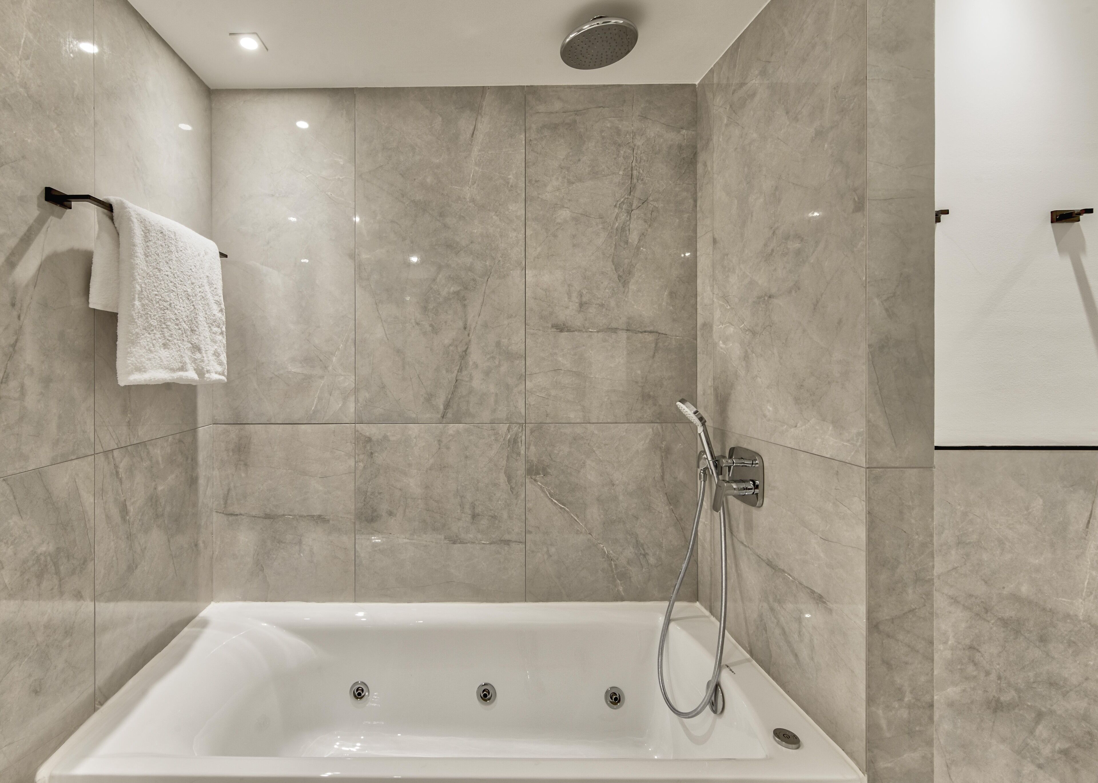 A modern bathroom with a freestanding bathtub, a handheld showerhead, and a towel rack.