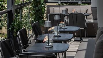Ulkoterassi, jossa on pöytiä ja tuoleja, sohva ja ruukkukasveja.
