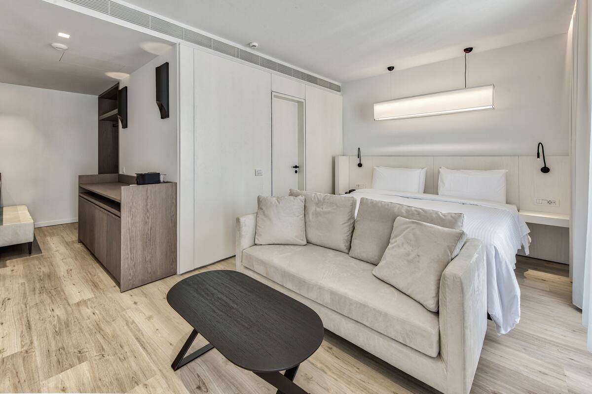 Une chambre à coucher moderne avec un lit, un canapé, un bureau et un banc.