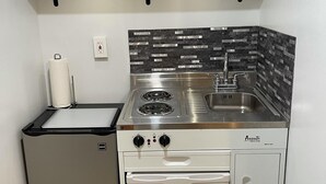 A compact kitchen with a stove, sink, and dishwasher, featuring a modern design and stainless steel appliances. - Tiny House Near Stone Mountain Park Minutes to Atlanta and FIFA.  (Lilburn)