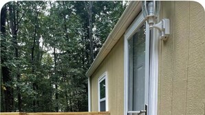 A wooden deck with a potted plant, a door with a glass panel, and a view of trees. - Tiny House Near Stone Mountain Park Minutes to Atlanta and FIFA.  (Lilburn)