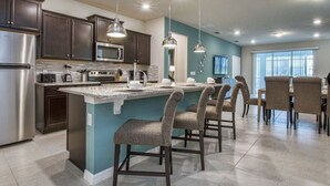 A modern kitchen with dark cabinets, stainless steel appliances, and a central island with bar stools.