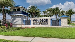 A sign for Windsor Island Resort with a clear view of the resort's entrance, palm trees, and a well-maintained lawn.